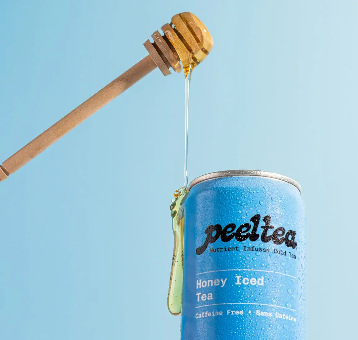 Blue can of 'peeltea' honey iced tea with a honey dipper dripping honey against a light blue background.