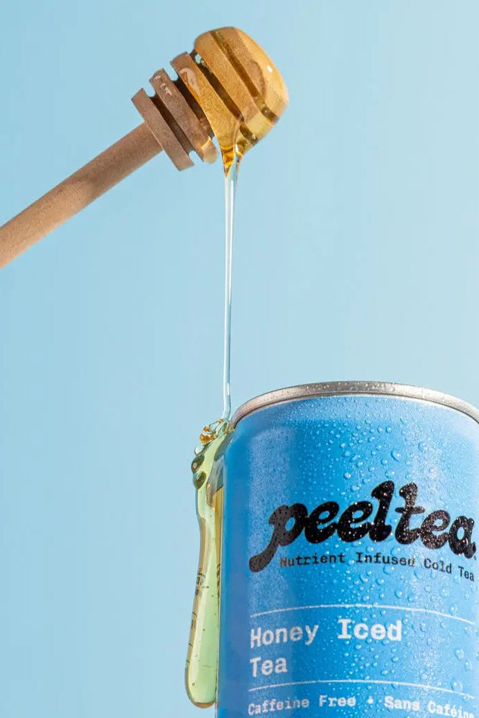 Blue can of PeelTea honey iced tea with a honey dipper dripping honey against a light blue background.
