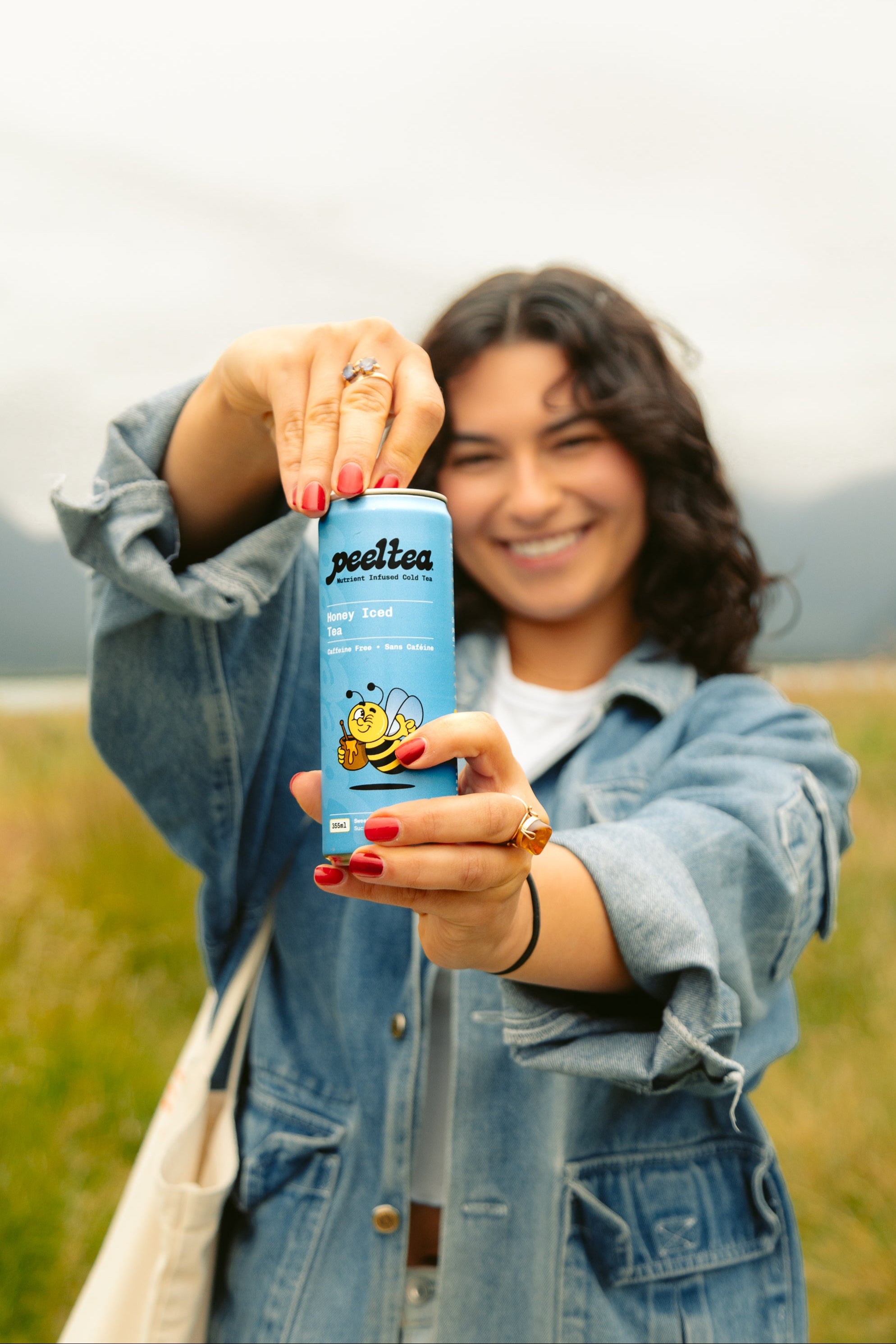 Woman cracking open a PeelTea Honey Iced Tea nutrient-infused cold tea can as a healthy refreshment.
