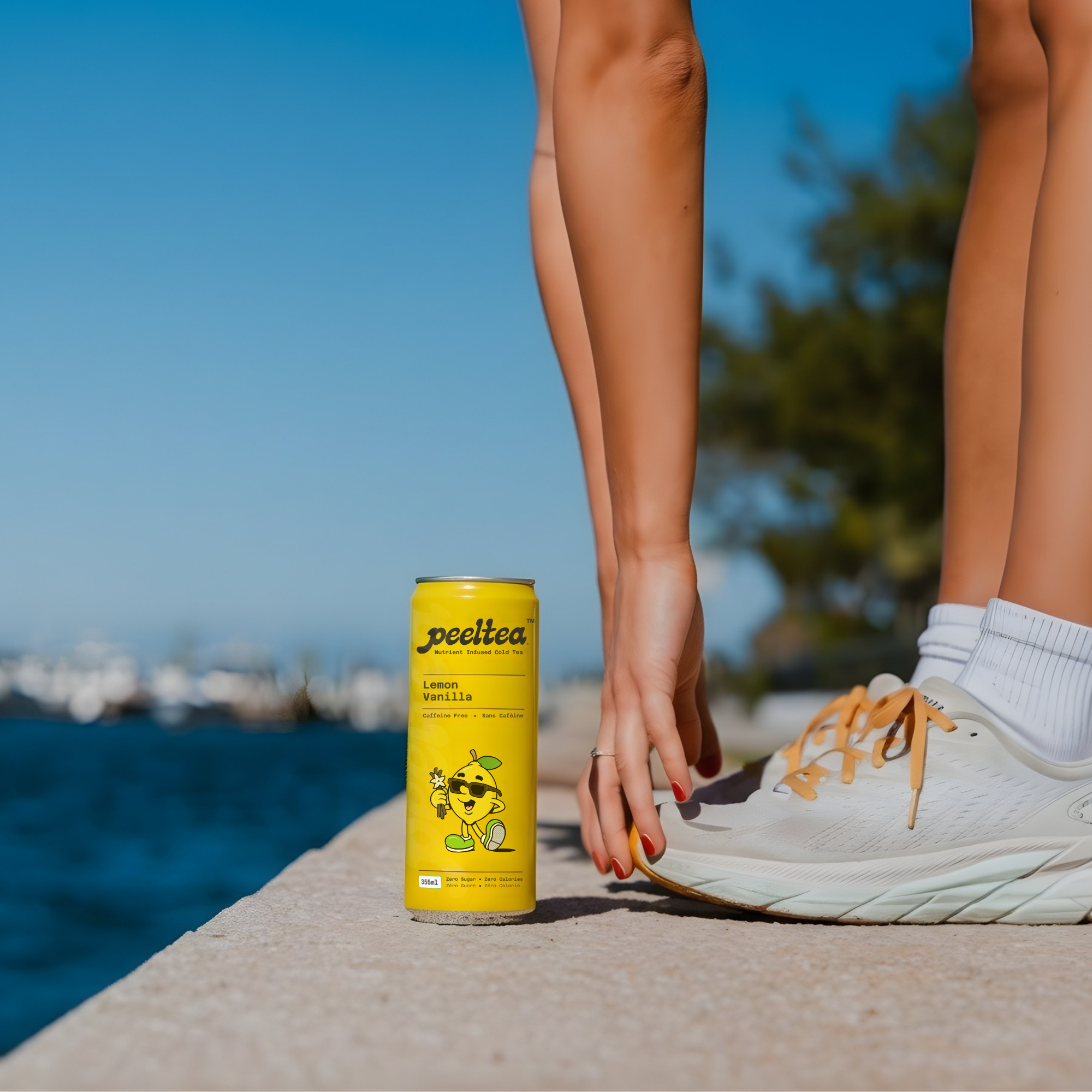 Person holding a can of PeelTea by a Vancouver Seawall with a scenic background