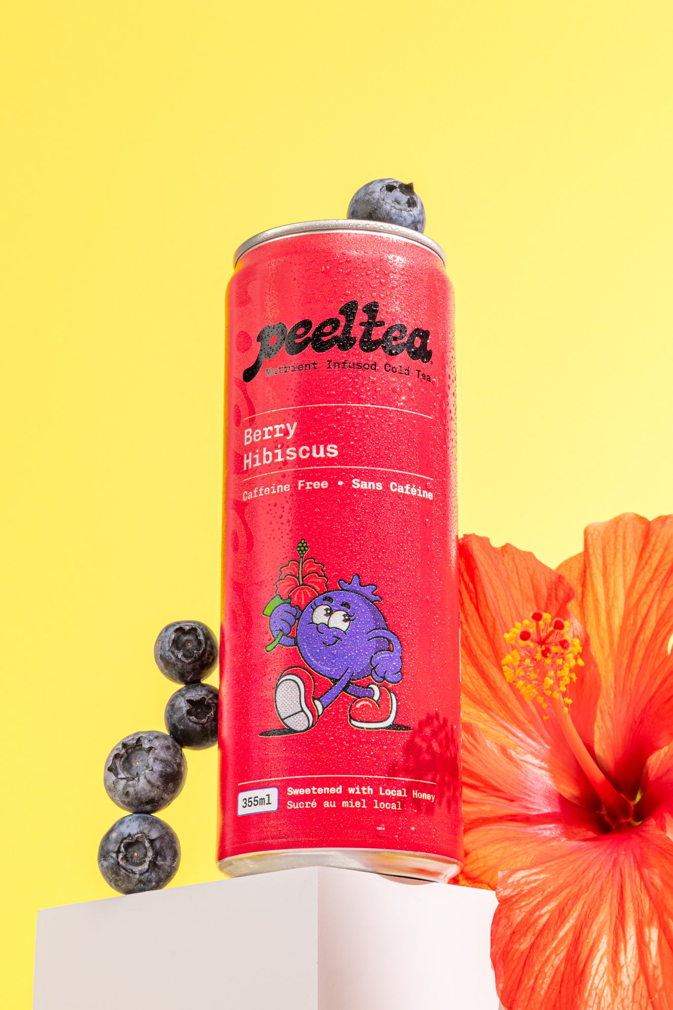 PeelTea Berry Hibiscus nutrient-infused cold tea can styled with blueberries and a hibiscus flower.