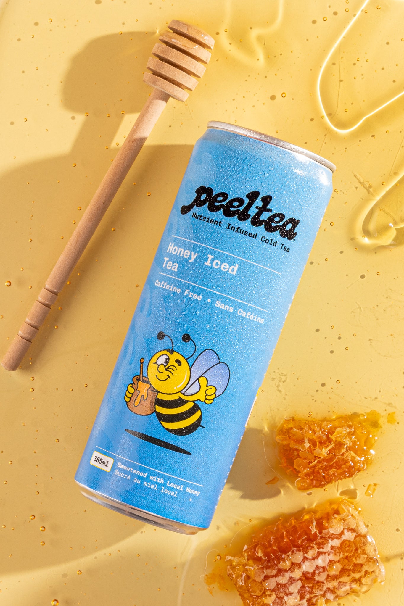 tudio image of PeelTea Honey Iced Tea can beside natural honeycomb and honey stick.
