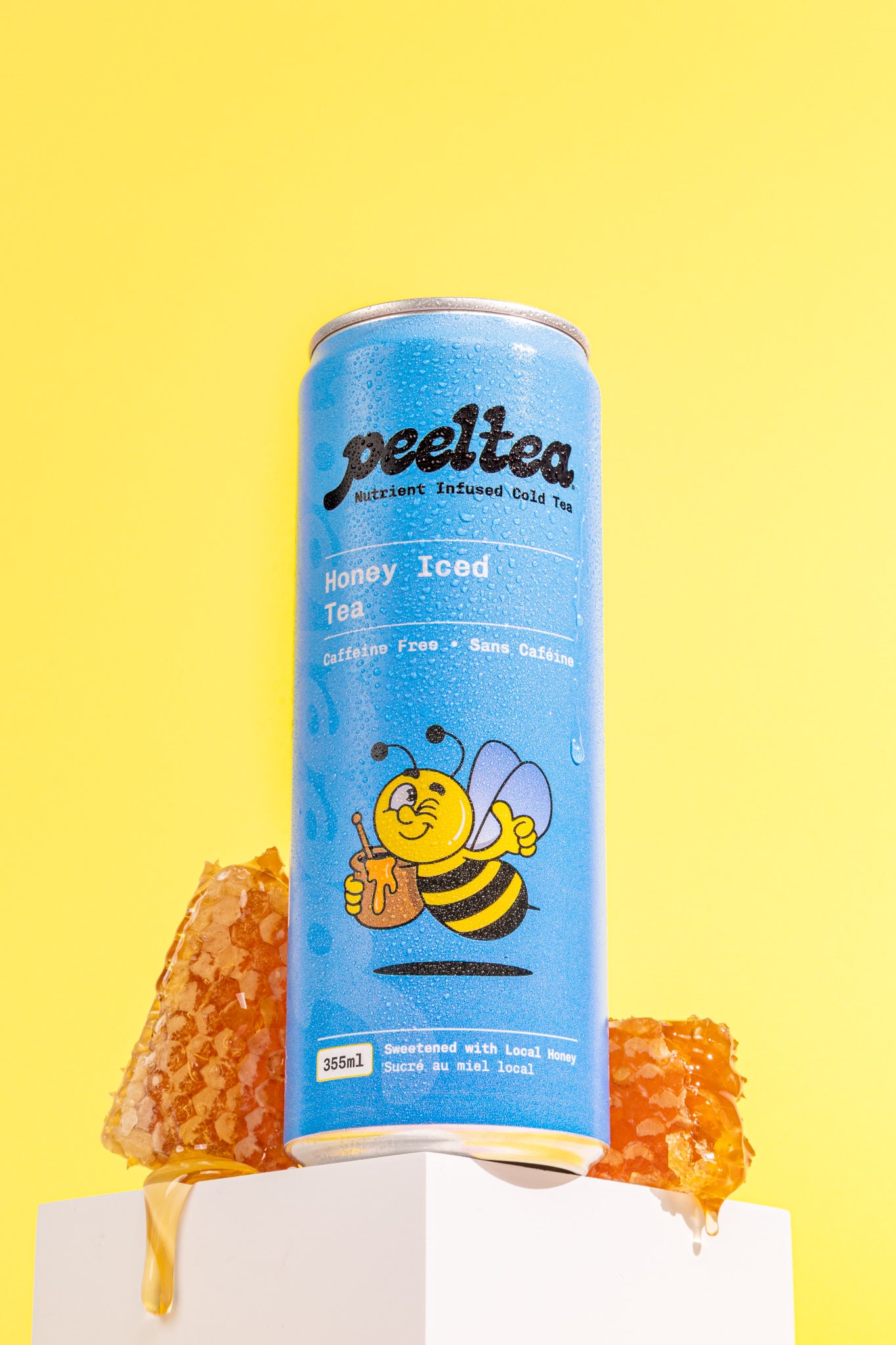 PeelTea Honey Iced Tea can displayed with fresh honeycombs as a healthy cold tea option.
